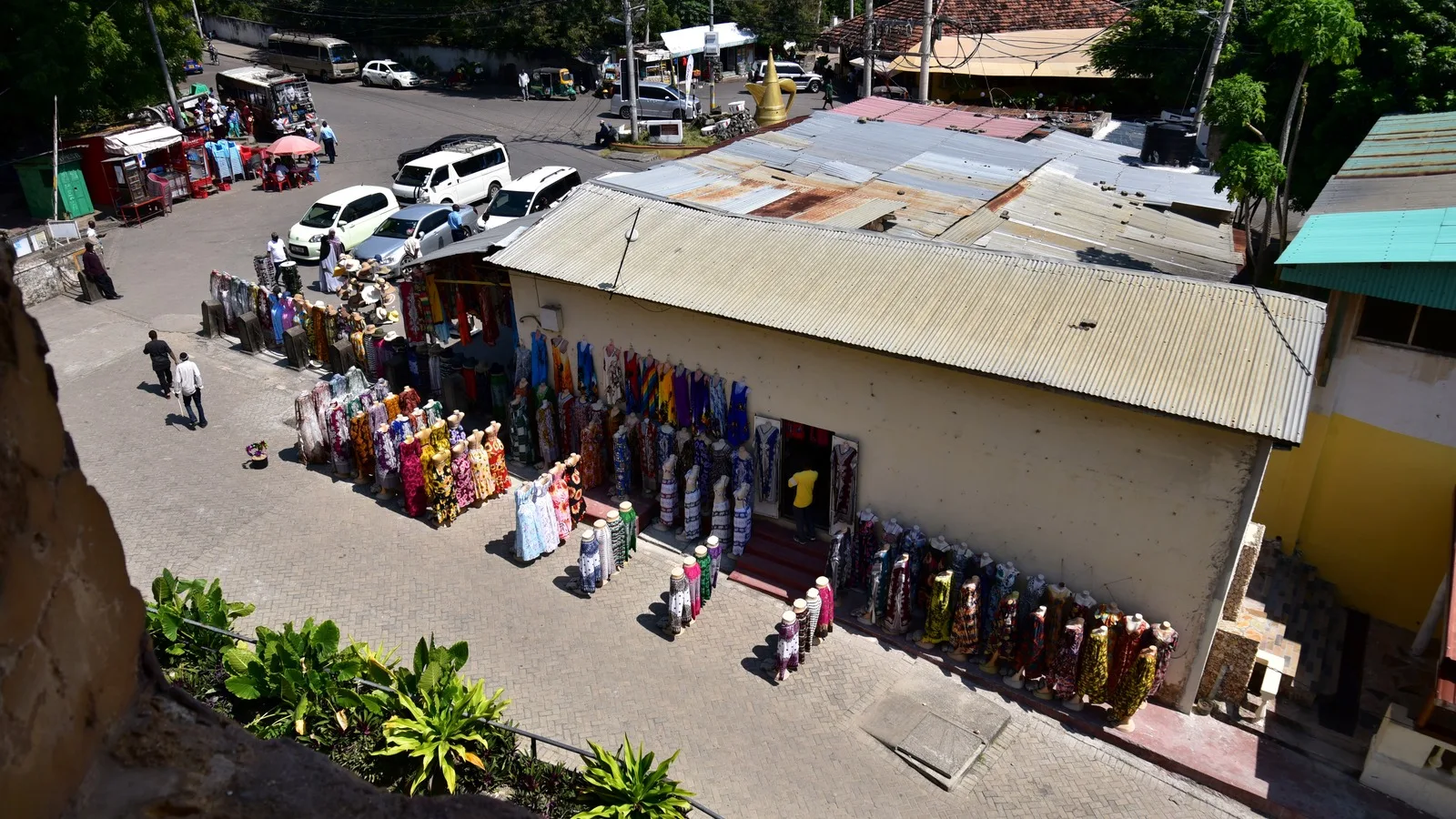 Brightly printed dresses hang along a shop wall below corrugated roofs in Mombasa Old Town.
